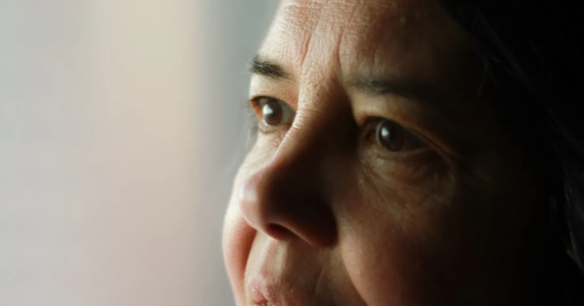 Mulher em momento de pausa e reflexão, olhando para a luz de uma janela